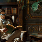 Dark Opulent Study Lifestyle Image of Attractive Man Reading in an Leather Arm Chair with Italico Luxury Glasses Valet sitting on the nearby side table