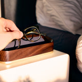 Bright Golden Hour Lifestyle Image of Italico Luxury Glasses Valet on a bedside table with a male hand placing glasses inside the valet